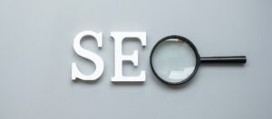 SEO wooden text and glass magnifying on gray background